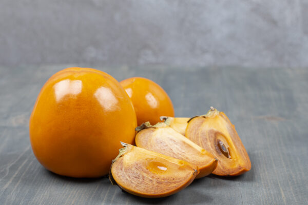 Sliced delicious persimmon in a wooden table Uchuva Liofilizada 15g